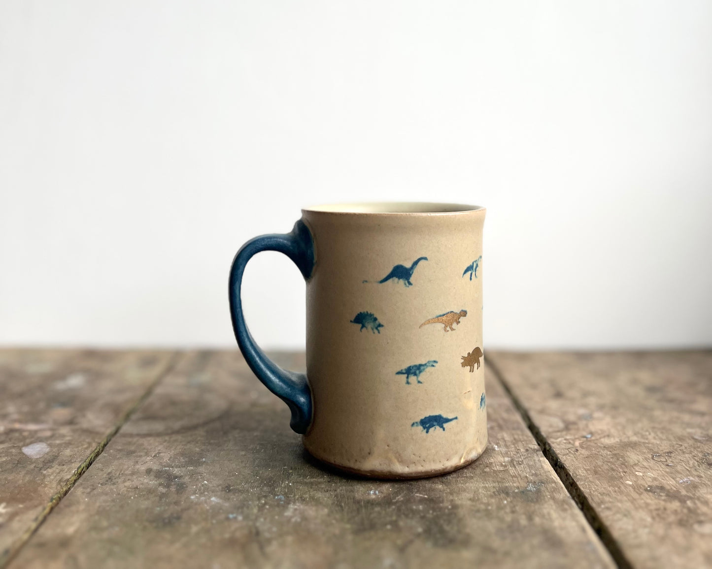 Mug with matte glaze and small blue and gold dinos