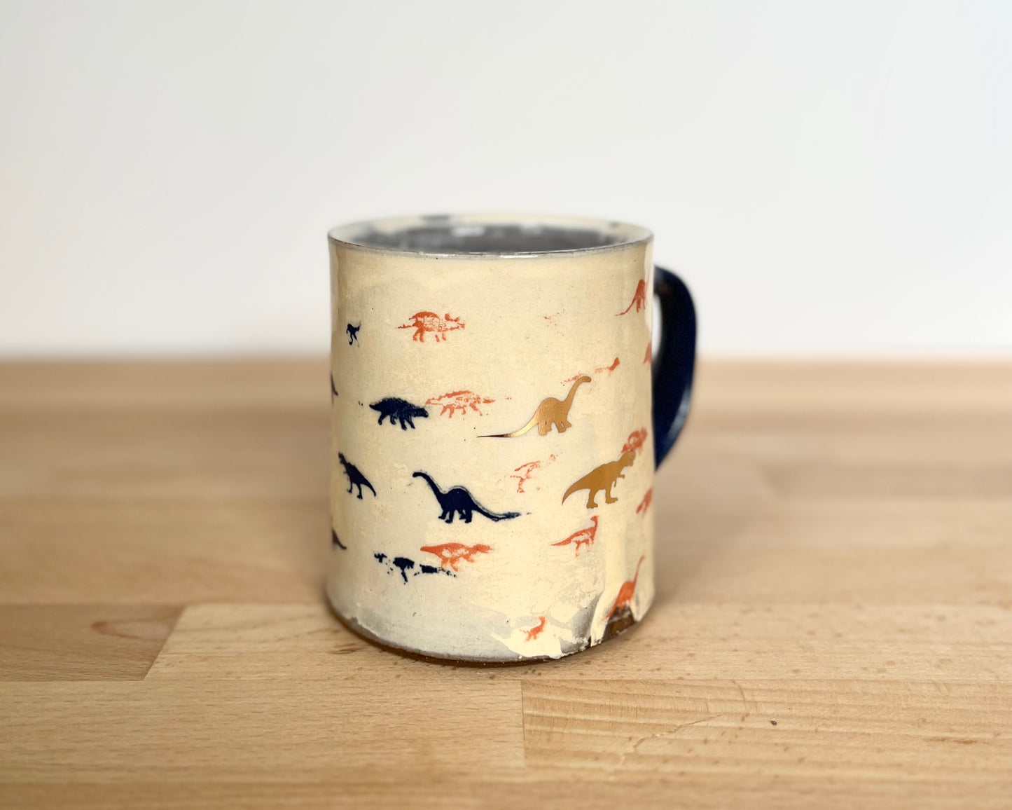 Mug with small orange, blue and gold dinos