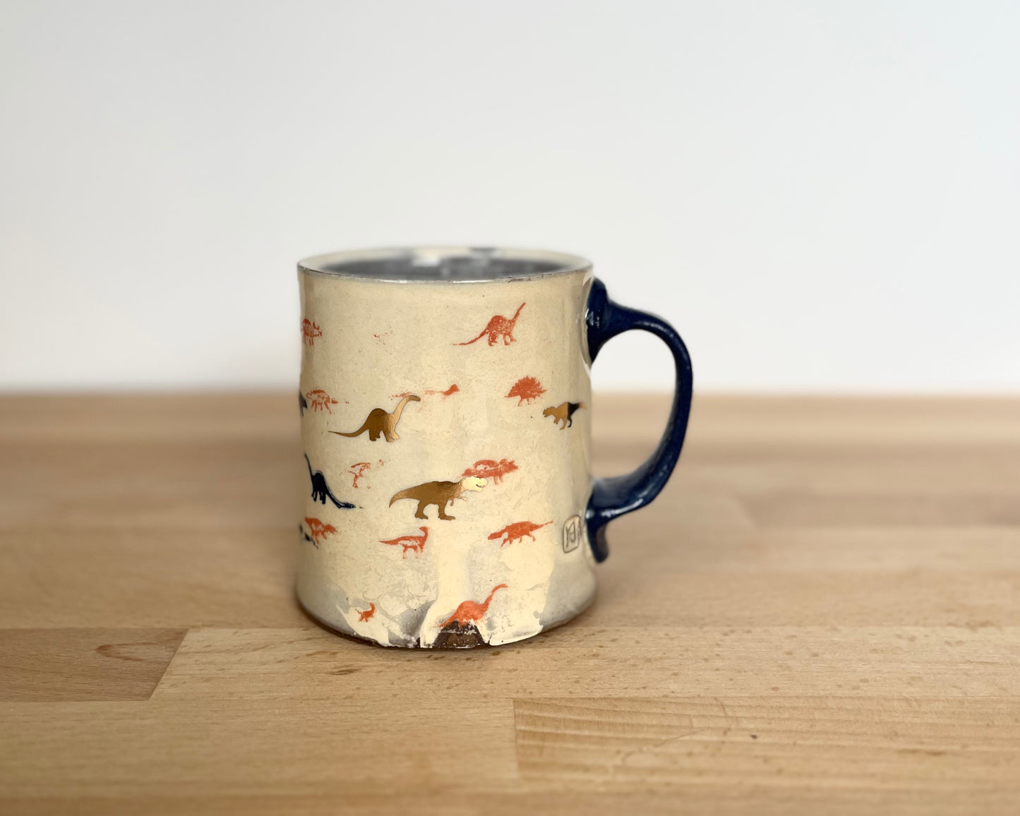 Mug with small orange, blue and gold dinos