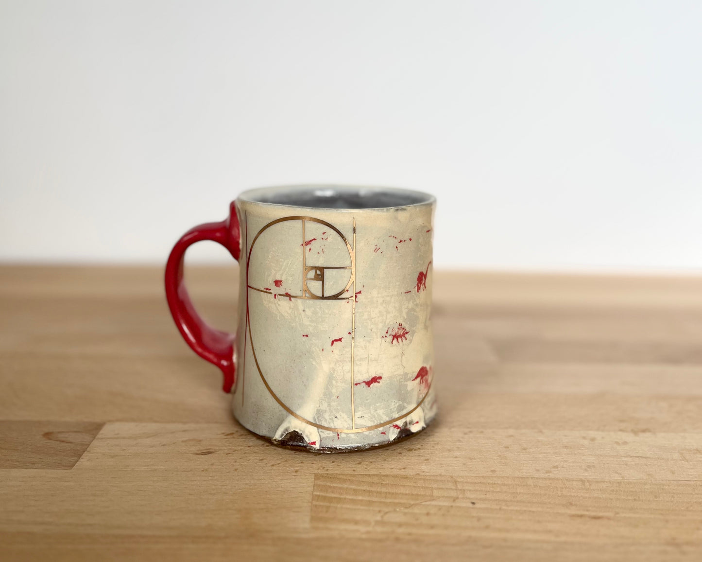 Mug with small red and gold dinos with Fibonacci spiral