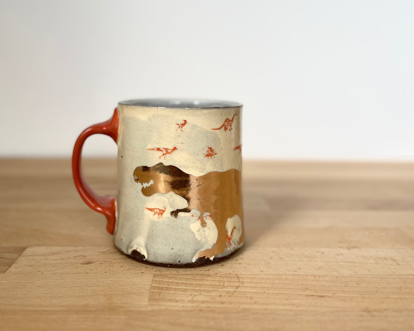 Mug with small orange and gold dinos and gold T-Rex