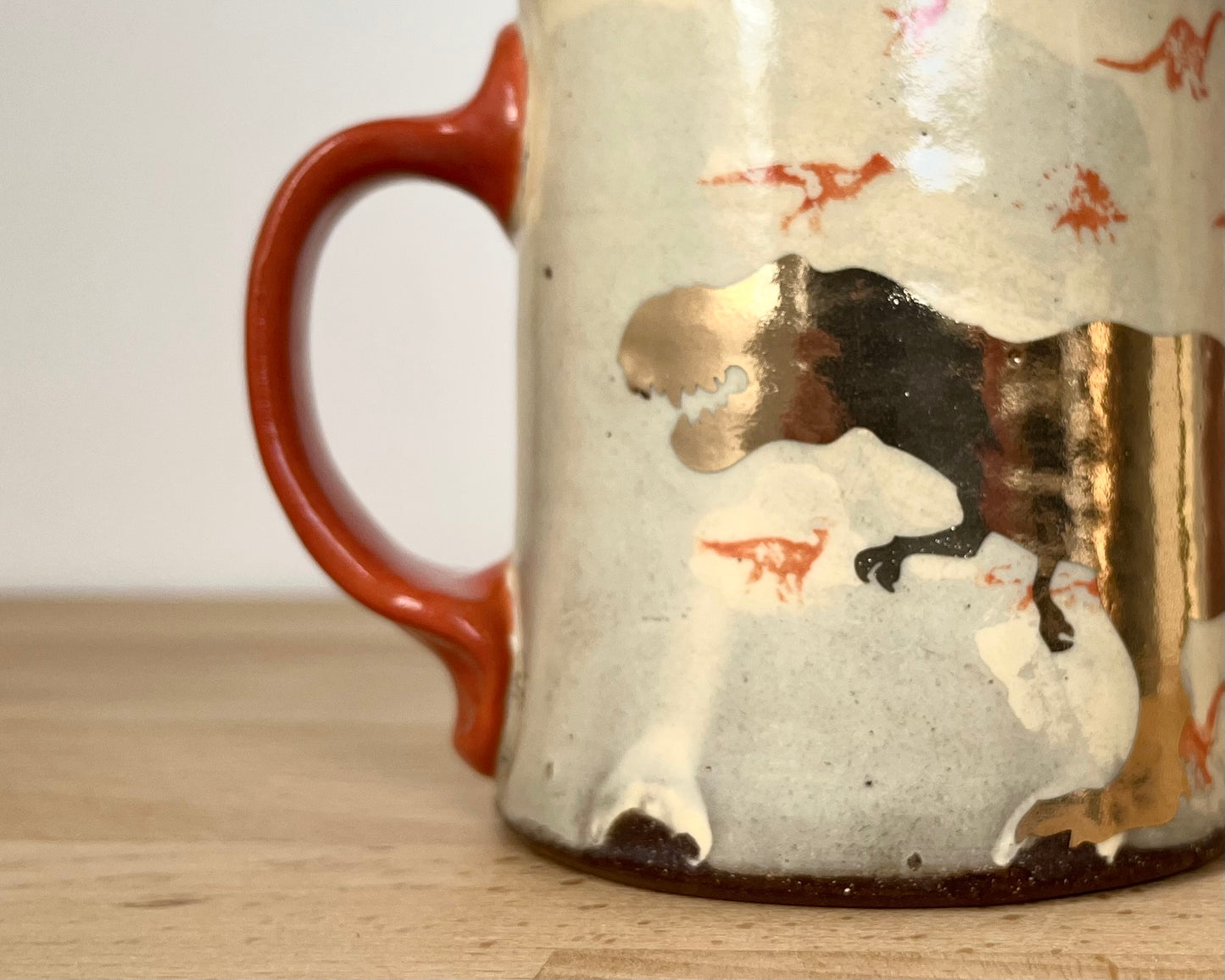 Mug with small orange and gold dinos and gold T-Rex