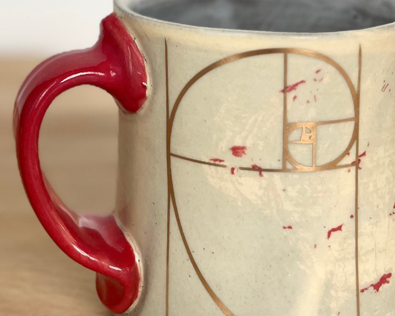 Mug with small red and gold dinos with Fibonacci spiral