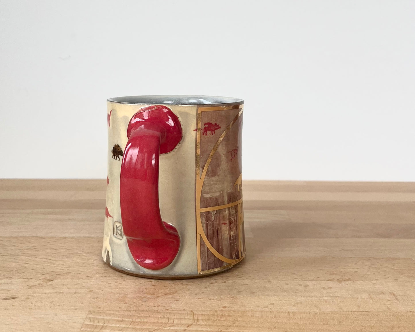 Mug with small red and gold dinos with fibonacci spiral