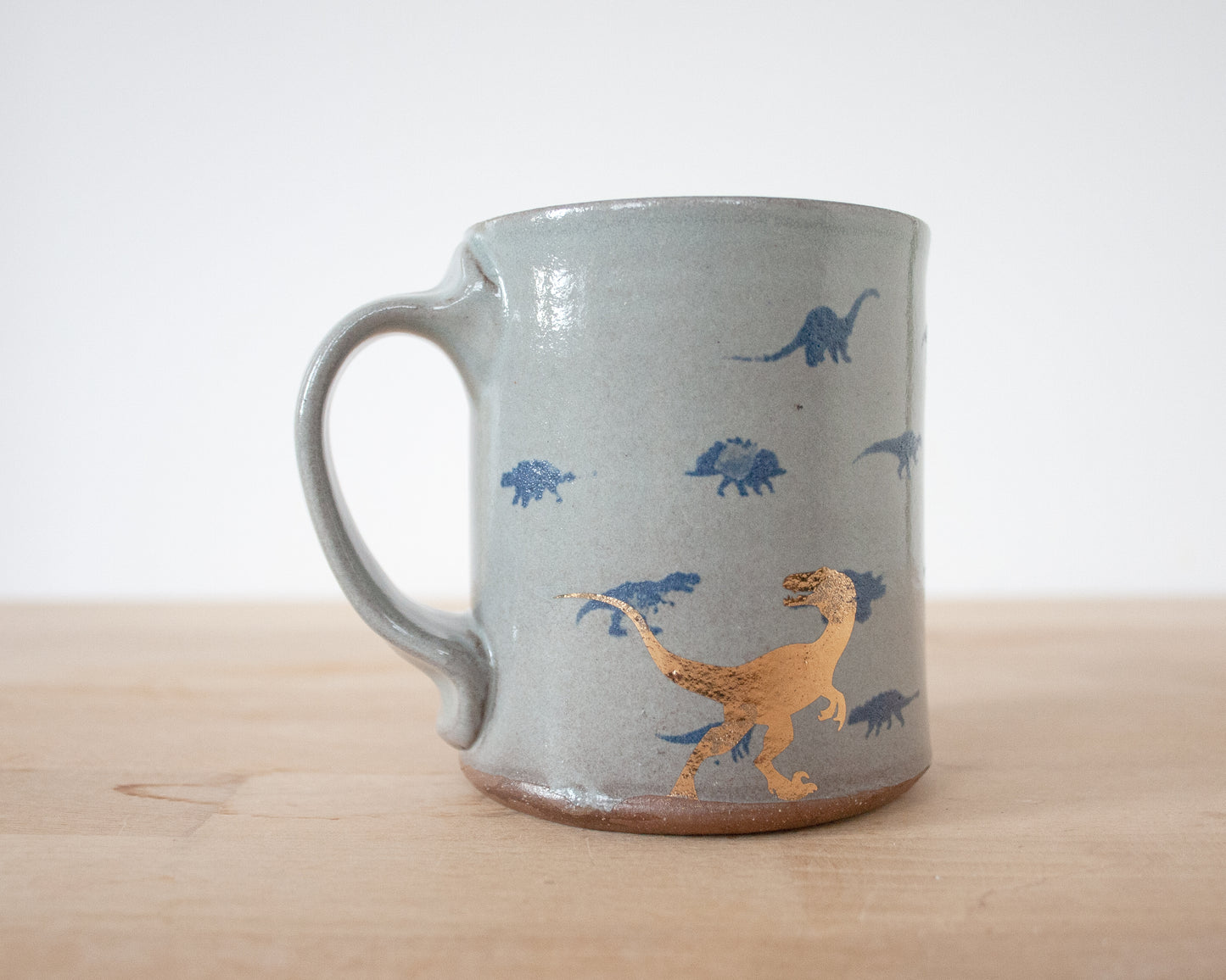 Gold Velociraptor Mug with small blue dinos