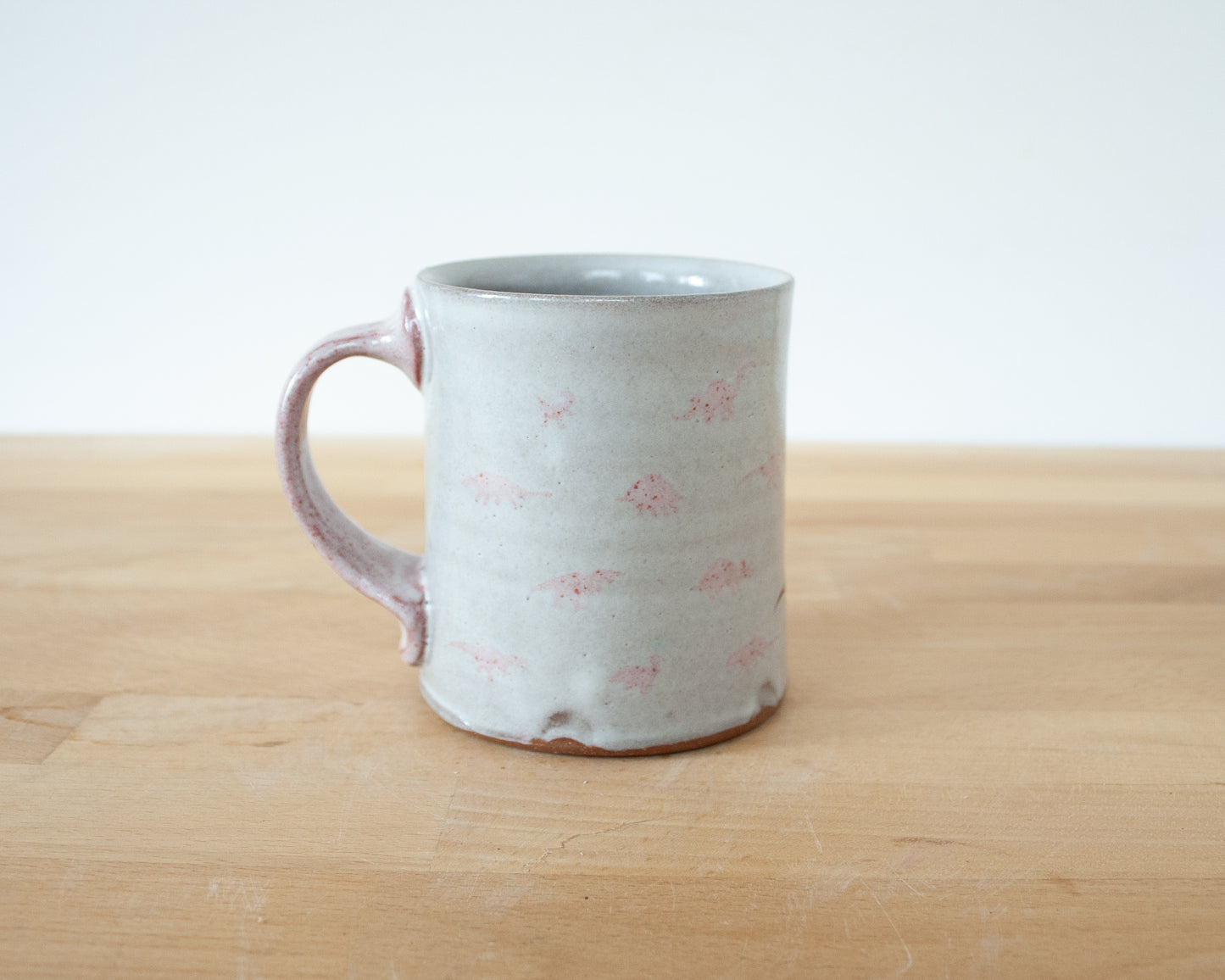 Mug with small pink and brown dinosaurs