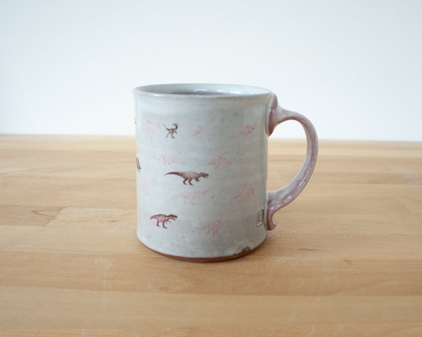 Mug with small pink and brown dinosaurs